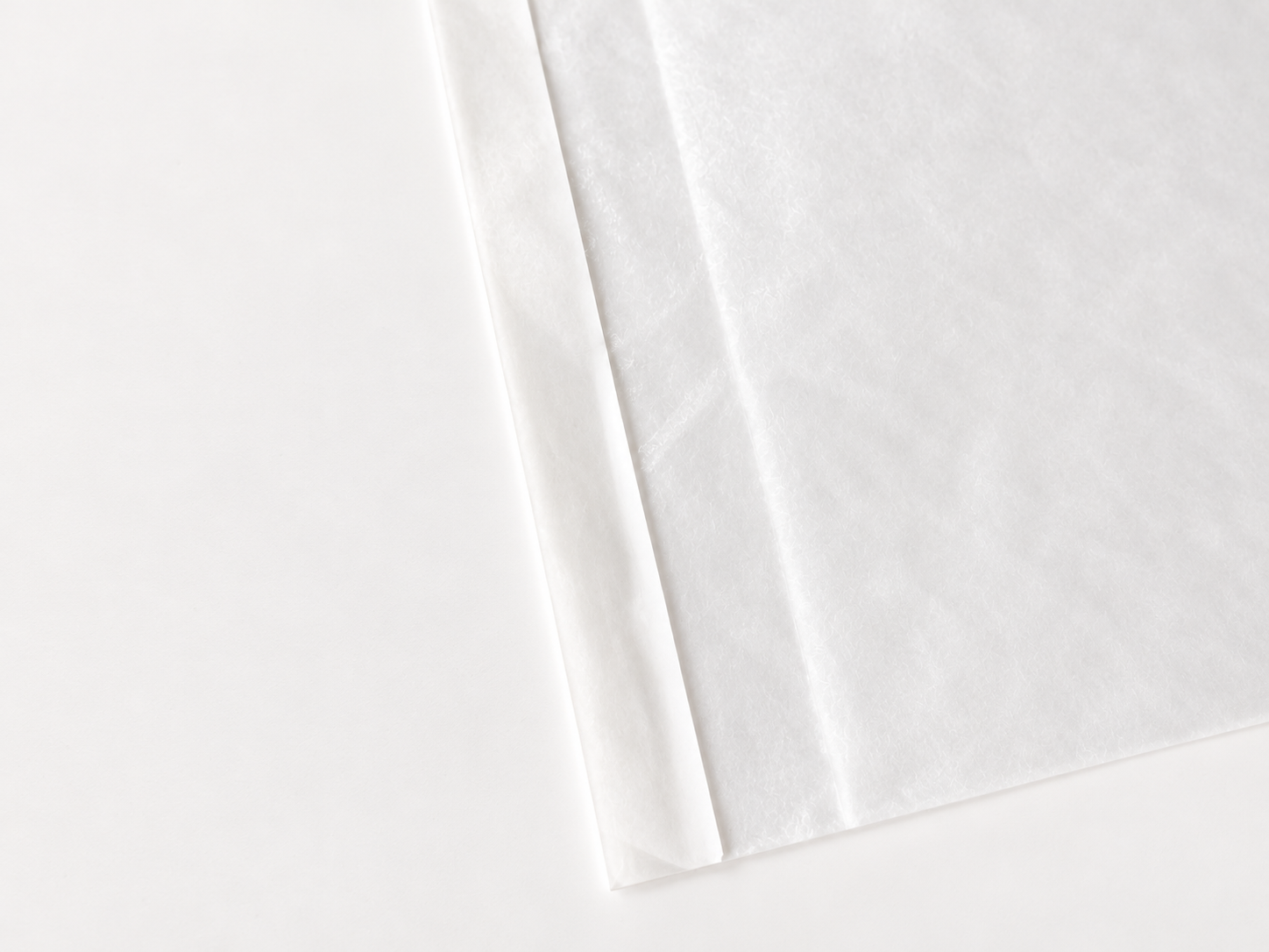 Close view of the folded seam on a translucent glassine paper bag.